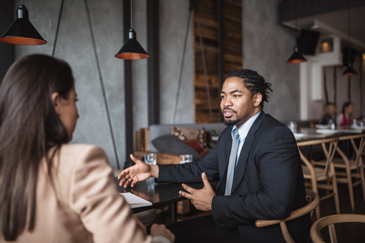 two-people-sitting-at-a-table-at-a-restauraunt-while-one-of-them-talks