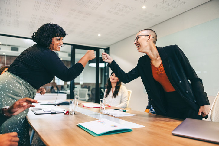 two-employees-fist-bumping-across-a-table