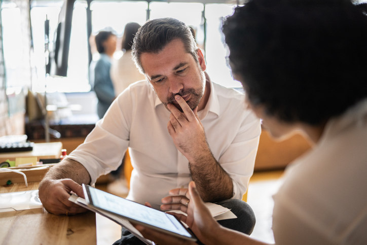 two-people-sitting-at-a-desk-looking-at-an-ipad