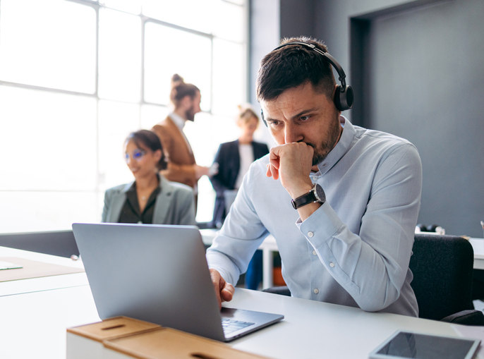 man-sitting-at-a-desk-looking-at-his-laptop-with-a-distressed-face