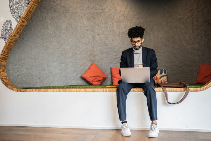 man-sitting-on-bench-while-looking-at-his-laptop