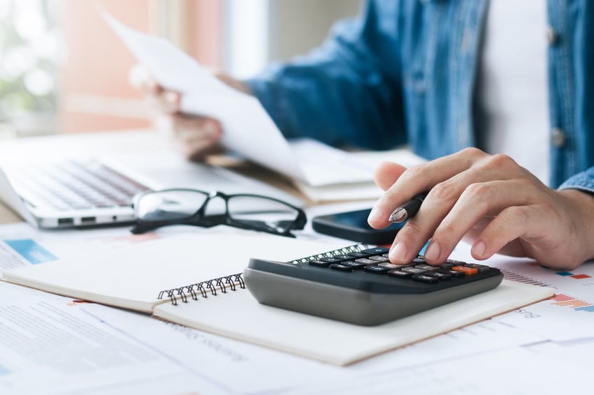 Person using calculator, reading a paper.