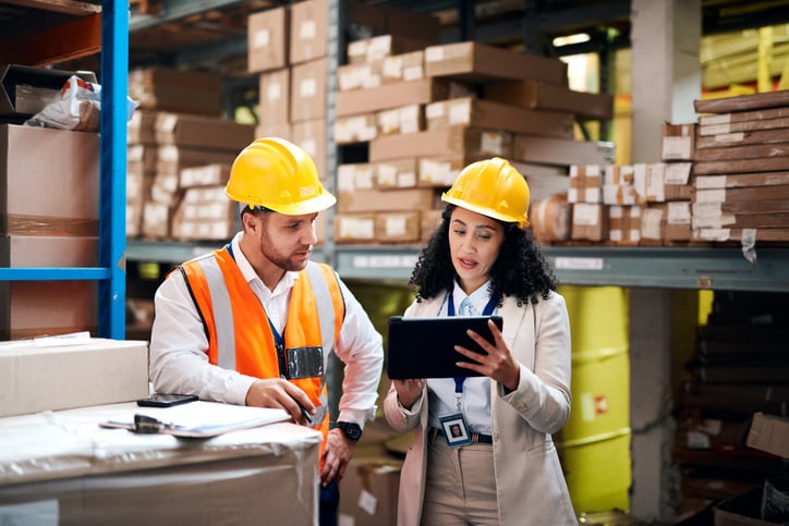 a-man-and-woman-in-a-warehouse-looking-at-an-ipad