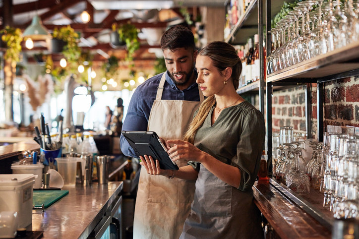 two-people-at-a-bar-looking-at-an-ipad-together