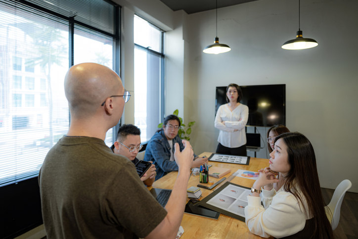 a-person-giving-a-presentation-around-a-table-of-people