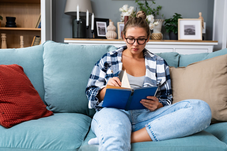 woman-sitting-on-couch-looking-through-a-book