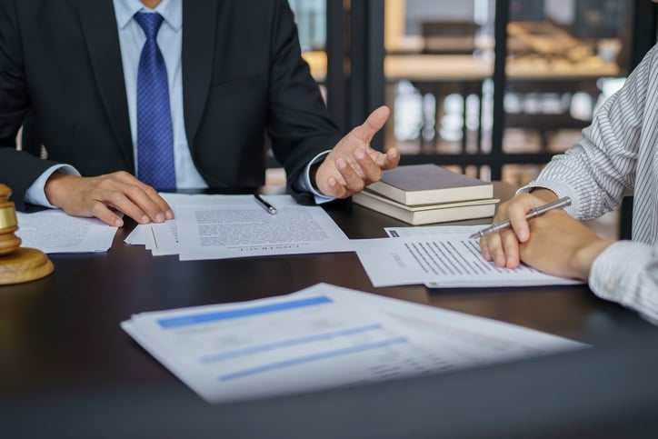 two-people-meet-at-a-desk-and-discuss-things-with-papers-on-the-table