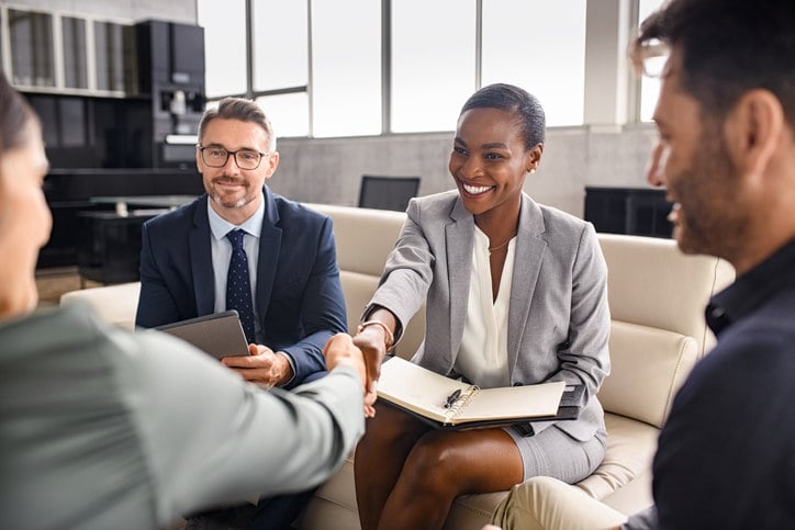 woman-sitting-on-couch-next-to-man-with-woman-shaking-hands-with-man