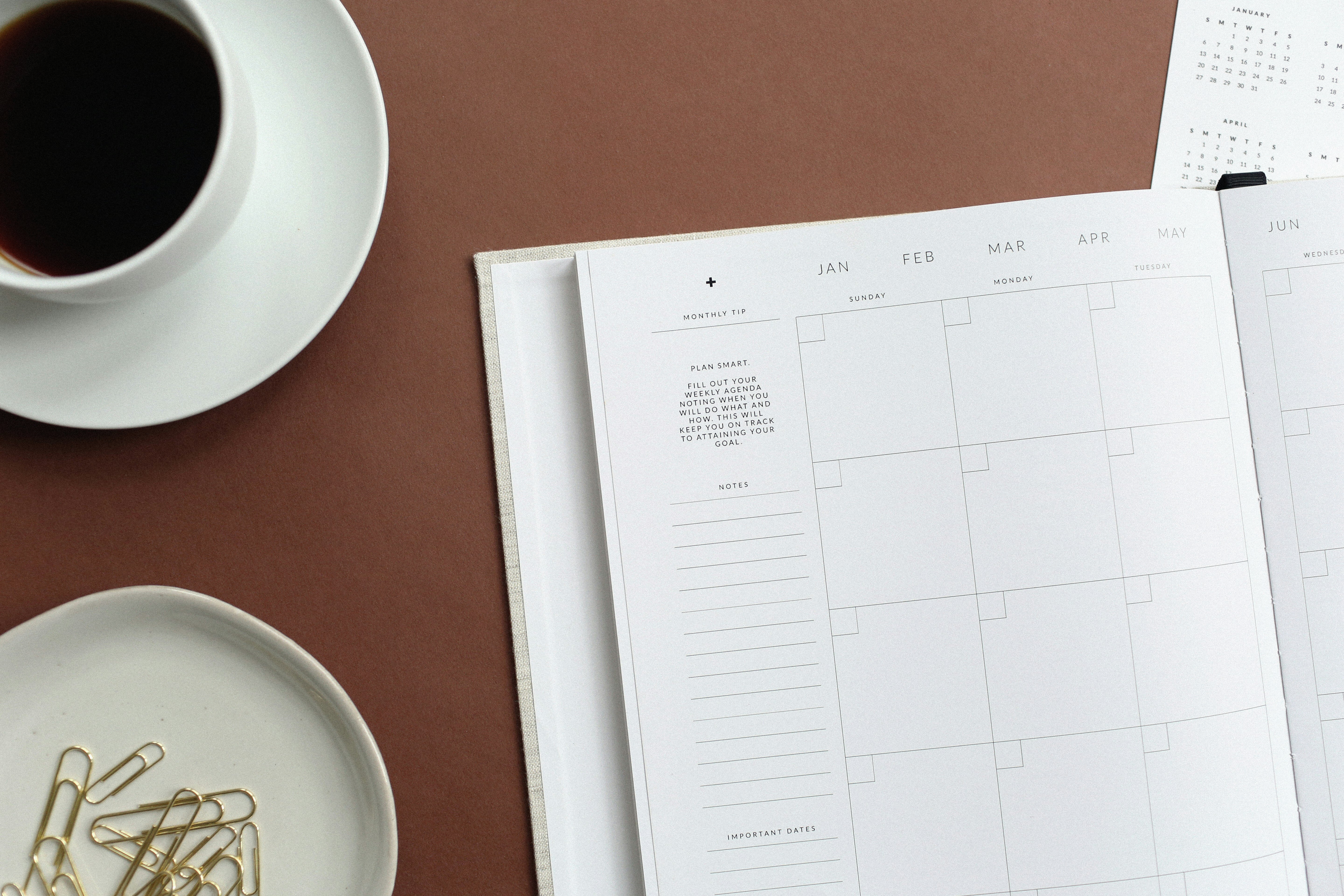 a-planner-mug-of-coffee-and-pile-of-paperclips-sit-together-on-a-desk